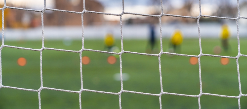 Campo de futebol visto através das redes do gol